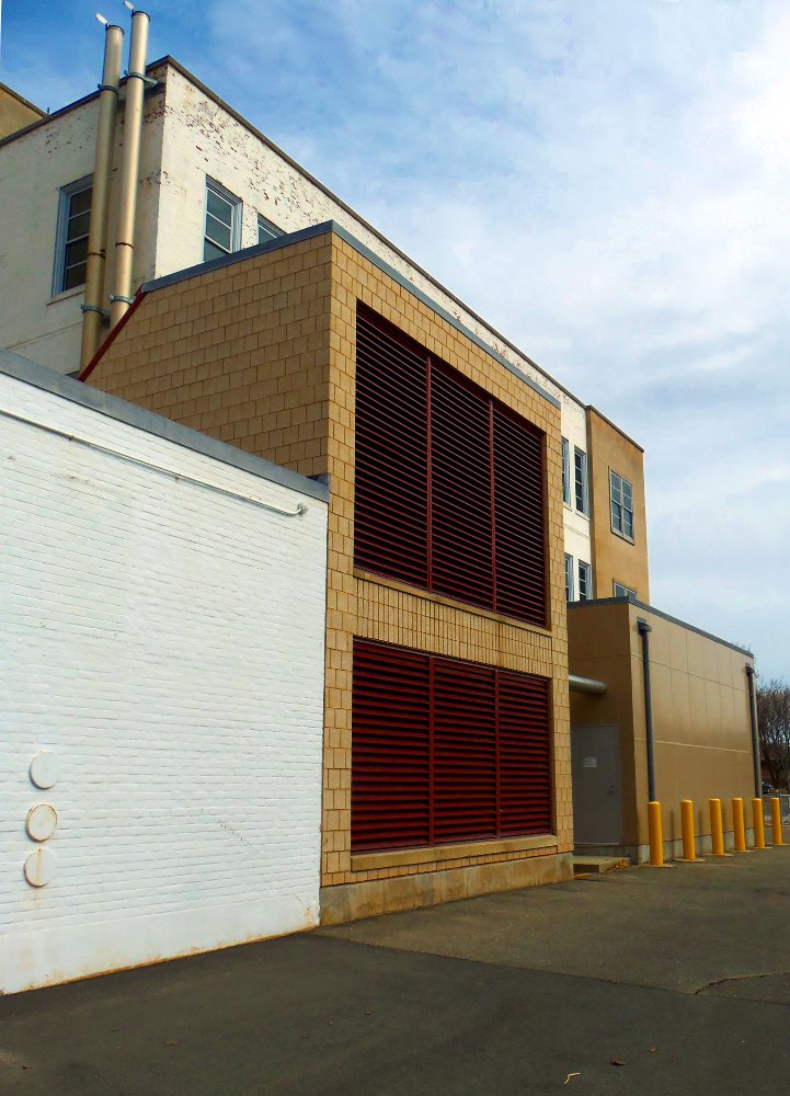 Image of a building with red louvers under a blue sky.