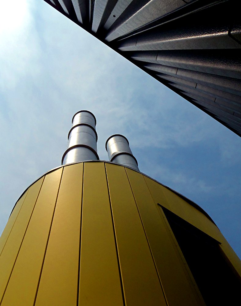 Image looking at a yellow stack extension against a blue sky.